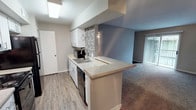 This 2-bedroom, 2-bathroom single-story unit offers a practical and modern layout with updated finishes throughout. The kitchen is a standout feature, designed in a galley style with white cabinetry, granite-style countertops, a mosaic tile backsplash, wood-look vinyl flooring, and black appliances including a refrigerator, range, and dishwasher. A peninsula counter opens directly to the living area, creating a seamless flow between spaces. The living room is generously sized, finished with neutral carpet and easy access to a sliding glass door that brings in natural light. Both bedrooms are carpeted and equipped with ceiling fans and windows fitted with blinds, providing comfort and natural light. Each of the two bathrooms features a tiled tub-surround with a decorative mosaic accent strip, wood-look flooring, and granite-style countertops with white cabinetry. The overall aesthetic is clean and contemporary, with neutral gray tones, white trim, and consistent finishes carried throughout the unit, creating a cohesive and move-in-ready living environment.