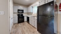 Located at 2500 Denzil Dr in Hopkinsville, Kentucky, this two-story residence offers a well-organized layout across two levels. The kitchen is outfitted with white cabinetry featuring decorative raised-panel detailing, light granite-style countertops, and a full suite of black appliances, including a range with over-the-range microwave, dishwasher, and refrigerator. Wood-look plank flooring runs through the kitchen and extends into adjoining main-floor areas, contributing to a cohesive, clean aesthetic. A separate living area on the main level benefits from natural light through a window and shares the same durable wood-look flooring.

The upper level houses multiple carpeted bedrooms, each finished with neutral tones and ceiling fans with integrated lighting. Several bedrooms include closets with double panel doors, providing practical storage. One room features French doors that open to a private balcony, offering a view of the surrounding outdoor area. The textured ceilings are consistent throughout the upper level, adding architectural detail.

Bathrooms are fitted with white vanities, wood-look tile flooring, and full tub-shower combinations with clean surround units. The overall interior palette is neutral and uniform, creating a calm, move-in-ready atmosphere throughout the home.