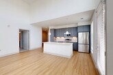 Located at 7400 S Addison Ct in Aurora, CO, this well-appointed 3-bedroom, 2-bathroom single-story home offers a thoughtfully designed layout with modern finishes throughout. The open-concept living, dining, and kitchen area serves as the heart of the home, featuring soaring double-height ceilings and an abundance of natural light streaming through large, floor-to-ceiling windows. Light wood flooring flows seamlessly across the main living spaces, complementing the bright, neutral color palette. The kitchen is a standout, equipped with sleek slate-gray cabinetry, a subway tile backsplash, stainless steel appliances including a refrigerator, range, and microwave, and a large central island with a white countertop and pendant lighting overhead. Both bathrooms are finished with large-format tile surrounds — one featuring a soaking tub and shower combination, the other a walk-in shower — each paired with gray vanities and light wood flooring. The bedrooms offer plush carpeting and generous closet space, with the primary bedroom providing a comfortable and well-sized retreat. Additional spaces include a laundry room, pantry, utility room, entrance foyer, and hallway, ensuring practical functionality throughout. The home's clean, contemporary design makes it a bright and versatile living space.