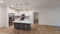 Located on South Boulevard in Charlotte's vibrant 28209 corridor, this single-floor residence offers a well-designed open-concept layout with contemporary finishes throughout. The kitchen serves as a central focal point, featuring white shaker cabinetry, granite countertops, a large island with a double stainless steel sink, subway tile backsplash, and a full suite of stainless steel appliances including a French door refrigerator, range, and built-in microwave. Pendant lighting above the island and recessed ceiling lights create a bright, inviting atmosphere. The kitchen flows seamlessly into the living area, which features warm wood-tone luxury vinyl plank flooring and a ceiling fan, with natural light streaming through wide windows fitted with blinds. Bedrooms are carpeted for comfort, each offering a ceiling fan, natural light, and neutral walls. The primary bathroom is appointed with a dual-sink vanity featuring granite countertops, gray cabinetry, a large mirror with vanity lighting, and a glass-enclosed shower. A secondary bathroom provides a tub-shower combination and matching granite finishes. The overall aesthetic is clean, modern, and cohesive, with consistent use of neutral tones and quality materials throughout.