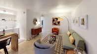Located at 1116 W Indian School Rd in Phoenix, Arizona, this single-story unit offers a thoughtfully designed layout that balances comfort and functionality. The living area showcases a distinct mid-century modern aesthetic, with clean white walls, light tile flooring, and an inviting arrangement of retro-inspired furnishings including a sage green sofa, an orange accent chair, and a classic hairpin-leg credenza. A patterned area rug and curated wall art add warmth and character to the space. Natural light filters in through vertical blinds on a sliding door, brightening the room with a soft, welcoming glow. The kitchen is efficiently designed and connects naturally to the dining area, which features bar-style seating and a compact, practical footprint ideal for everyday use. The bedroom provides a serene retreat, furnished with a queen-sized bed accented by colorful throw pillows and complementary abstract artwork. A window with vertical blinds allows natural light while maintaining privacy. The bathroom is cleanly finished with light tile flooring, a wall-mounted vanity, and a separate water closet, offering a functional and organized layout. Overall, the space presents a cohesive mid-century modern character with a comfortable, livable ambiance throughout.