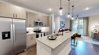 Located in Lawrenceville, GA, this well-appointed 2-bedroom, 2-bathroom residence offers a thoughtfully designed single-level layout that maximizes both functionality and style. The open-concept living and kitchen area serves as the heart of the home, anchored by a generous granite-topped island with an undermount sink and pendant globe lighting that adds a contemporary touch. Light wood-tone cabinetry, stainless steel appliances — including a refrigerator, range, and microwave — and a classic tile backsplash complete the kitchen. Rich hardwood-style flooring runs throughout the main living areas, transitioning to plush carpet in the bedrooms. The living room provides ample space and connects seamlessly to the kitchen and dining area, with natural light filtering in through large windows. The primary bedroom is a comfortable retreat featuring a ceiling fan, natural light from a large window, and direct access to a well-sized bathroom with granite vanity countertops and wood-tone cabinetry. Each bedroom includes a dedicated closet with wire shelving systems for organized storage. The second bathroom mirrors the same refined finishes. Bold navy accent doors add a distinctive design detail throughout the home, contributing to its modern, curated aesthetic.