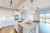 Located at 3400 Sharon Road in Charlotte's desirable 28211 zip code, this well-appointed 2-bedroom, 5-bathroom residence offers a thoughtfully designed single-floor layout with a bright, open feel throughout. The gourmet kitchen is a standout feature, showcasing white shaker cabinetry, quartz countertops, stainless steel appliances including a double wall oven and French door refrigerator, a large center island with a wine rack, and stylish pendant lighting above — all set atop rich hardwood flooring. The open-plan living and dining area flows naturally from the kitchen, highlighted by a built-in arched niche with shelving, a built-in desk area, and floor-to-ceiling windows that flood the space with natural light and offer expansive city views. The spacious primary bedroom features plush carpeting, a tray ceiling, direct access to a well-appointed en-suite bathroom with a soaking tub finished in travertine tile, and a generous walk-in closet with adjustable shelving. The second bedroom also enjoys large windows with city views. Five bathrooms in total — including a sleek powder room with a pedestal sink and round mirror — provide exceptional convenience. A dedicated laundry room with a full-size washer and dryer completes this refined urban residence.