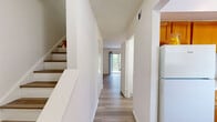 Located in Colonial Heights, Virginia, this two-story, two-bedroom, two-bathroom home offers a practical and well-organized layout across two floors. The main level features light-toned, wood-style flooring throughout, lending a clean and cohesive feel to the space. The combined dining and living area is bright and open, highlighted by a sliding glass door that opens to a private deck with wooded views, allowing natural light to fill the room. Adjacent to the living area, the galley-style kitchen is equipped with warm wood cabinetry, a gas range, dishwasher, refrigerator, and a window that brings in additional natural light. A hallway connects the main living spaces, with a full bathroom and closet storage also found on this floor. The staircase leads to the upper level, where both bedrooms are located. The generously sized primary bedroom features a large double-door closet and soft carpeting, while the second bedroom also offers carpeted flooring, a closet, and a window with natural light. A second full bathroom on the upper level includes a tub-shower combination. Throughout the home, clean white walls, ample closet space, and consistent finishes create a tidy, move-in-ready environment.