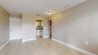 Located at 1666 18th Ave N in Saint Petersburg, Florida, this single-story home offers a straightforward and functional layout finished consistently with light-toned ceramic tile flooring throughout. The interior is characterized by neutral beige walls, white baseboards, and flush-mount ceiling lighting, creating a clean and cohesive aesthetic.

The living area is open and well-proportioned, with a window fitted with horizontal blinds that allows natural light to brighten the space. A textured ceiling adds a classic Florida residential touch. The room connects conveniently to other areas of the home, including a hallway that leads to the bedroom and bathroom.

The kitchen is efficiently designed in a U-shaped configuration, featuring white cabinetry, dark laminate countertops, a double-basin sink beneath a window, and white appliances including an electric range, over-the-range microwave, and refrigerator. The layout maximizes available counter and storage space.

The bedroom is a comfortable, light-filled room with tile flooring, a large window overlooking the outdoors, and access to a reach-in closet with a double-door entry and a rod for hanging storage. The bathroom includes a full-size tub and shower combination with clean white tile surround and chrome fixtures. Entry to the home is through a charming paneled exterior door.