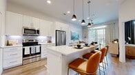 Located at 9921 W Valley Ranch Pkwy in Irving, TX, this well-appointed one-bedroom, one-bathroom residence offers a thoughtfully designed open-concept layout with modern finishes throughout. Light wood-tone flooring flows seamlessly across the entire space, complementing the bright, neutral color palette.

The kitchen and living area form the heart of the home, anchored by a generous island with quartz countertops, an undermount sink, and built-in dishwasher — ideal for both meal prep and casual dining with bar seating. White shaker cabinetry, a subway tile backsplash, and a full suite of stainless steel appliances, including a French door refrigerator, electric range, and over-the-range microwave, complete the kitchen. Stylish pendant lighting adds a contemporary touch overhead.

The living area flows naturally toward a large sliding glass door that opens to a private balcony, flooding the space with natural light and offering outdoor views. The bedroom is a comfortable retreat featuring a barn-style sliding door, a sliding glass door with outdoor access, and warm, inviting finishes. The bathroom features white cabinetry, a quartz vanity, and a tub-shower combination. Additional conveniences include a dedicated closet and in-unit laundry.