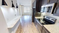 This 430 square foot apartment in Fort Worth, TX, exemplifies modern efficiency in a compact space. The single-floor layout maximizes functionality, featuring an open-concept design that creates a sense of spaciousness. The kitchen is a standout element, boasting dark wood cabinetry, stainless steel appliances, and a sleek countertop, perfect for culinary enthusiasts. Pendant lighting adds a touch of contemporary style.

The living area is bathed in natural light from large windows, complemented by a modern ceiling fan. Wood-look flooring throughout unifies the space and adds warmth. The bathroom is designed with attention to detail, featuring a glass-enclosed shower and modern fixtures. A closet provides essential storage space.

The apartment's neutral color palette, primarily whites and grays, creates a clean, fresh ambiance. The combination of functionality and style makes this space ideal for urban living, offering all necessities in a well-designed, compact format. The overall aesthetic is one of contemporary minimalism, perfect for those seeking a low-maintenance yet stylish living environment.
