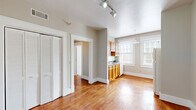 Located at 855 Mulberry St in historic Macon, Georgia, this well-appointed one-bedroom, one-bathroom unit offers an efficient and comfortable single-floor layout. Rich hardwood flooring flows throughout the space, lending warmth and cohesion to every room.

The open living area is bright and welcoming, benefiting from natural light streaming through large double-hung windows framed by clean white trim. Track lighting overhead provides additional illumination. A louvered bi-fold closet door adds a classic touch and practical storage to the living space.

The kitchen is thoughtfully designed, featuring warm honey-toned wood cabinetry, dark speckled countertops, a stainless steel sink, and a gas range. Dual windows in the kitchen allow abundant natural light, creating an airy cooking environment. A dishwasher and ample upper and lower cabinet storage complete the space.

The bedroom is a comfortable retreat, finished with the same gleaming hardwood floors, a ceiling fan with light fixture, and a bright window. Generous closet space is provided, with a total of three closets throughout the unit, along with dedicated laundry and hallway areas for added convenience.

The bathroom showcases classic white subway tile surrounding a full bathtub, accented by a bold dark tile border, black floor tile, and a window for natural ventilation. The overall aesthetic is clean, timeless, and move-in ready.