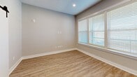 Located at 205 Hollis Rd in Charlotte, NC, this thoughtfully designed unit offers a modern aesthetic with high-quality finishes across a single floor. The open-concept kitchen and living area serves as the heart of the space, featuring light hardwood-style flooring, recessed lighting, and large windows that invite abundant natural light. The kitchen is well-appointed with shaker-style cabinetry in a soft grey-white palette, dark countertops, stainless steel appliances, a white subway tile backsplash, a central island, and a built-in wine rack — making it as functional as it is stylish. The living area benefits from a wide triple-panel window with clean white trim, reinforcing the bright and airy atmosphere. Two bathrooms provide refined comfort; the primary bath features a glass-enclosed walk-in shower adorned with floor-to-ceiling marble-look tile and a built-in bench, while the secondary bathroom showcases a white vanity with dark countertops, black matte hardware, and coordinating tile flooring. A dedicated walk-in closet offers multi-tier rod storage and shelving atop durable hardwood-style flooring, delivering practical organization. Neutral wall tones and consistent flooring throughout create a cohesive, contemporary feel.