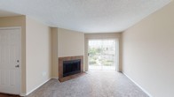 Located at 2945 Layfair Dr in Flowood, Mississippi, this single-story unit offers a comfortable and functional layout with a warm, neutral color palette throughout. The living room serves as the centerpiece of the space, featuring a tile-surround fireplace and a large sliding glass door that opens to a private patio, filling the room with natural light and offering pleasant outdoor views. Plush carpet underfoot adds warmth and comfort to the living and bedroom areas.

The kitchen is efficiently designed with white cabinetry, granite-style countertops, hardwood-style flooring, and white appliances including a refrigerator, range, and oven. A peninsula counter separates the kitchen from the adjacent living and dining area, creating an open, connected feel ideal for everyday living. The adjoining space provides ample room and easy access to a walk-in closet area.

The bedroom is well-sized, with a large window that invites natural light and provides a view of the surrounding greenery, complemented by soft carpet flooring. The bathroom is clean and functional, featuring white cabinetry with granite-style countertops, a single-basin sink, and a full tub-shower combo with classic white tile surround and hardwood-style flooring. This unit combines practical design with comfortable finishes throughout.