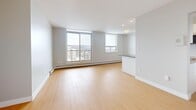 Located at 205 Hunter St W in Hamilton, Ontario, this thoughtfully designed two-bedroom, two-bathroom unit offers a clean, modern aesthetic throughout. Light hardwood flooring flows seamlessly across the entire space, lending warmth and continuity to every room.

The open-concept living and dining area is bright and airy, anchored by large windows that frame expansive city views. The kitchen is well-appointed with white flat-panel cabinetry, dark grey countertops, stainless steel appliances including a refrigerator, range, built-in microwave, and dishwasher, and a breakfast bar peninsula that connects effortlessly to the living space.

Both bedrooms are comfortably sized with large windows that bring in natural light and offer elevated city views. The spacious primary bedroom includes a closet with sliding doors. Baseboard heating runs along the perimeter of both bedrooms, the living room, and the kitchen area, ensuring year-round comfort.

The two bathrooms are finished in a crisp, contemporary style. The main bathroom features a soaking tub with white tile surround, a large mirror, and a white vanity with dark countertop. The second bathroom offers a matching vanity and tile flooring. Neutral grey tones throughout the unit create a calm, cohesive atmosphere ideal for modern urban living.