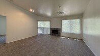 This 810-square-foot, single-floor apartment offers a practical and comfortable layout with 2 bedrooms, 2 bathrooms, 2 closets, and a combined kitchen and living room. The living room is a standout space, featuring a tile-surround wood-burning fireplace flanked by large windows with vertical blinds that invite abundant natural light and outdoor greenery views. A ceiling fan and sliding glass door leading to a private balcony complete this welcoming area. The kitchen features light wood cabinetry, a peninsula with a built-in sink and white countertops, wood-look vinyl flooring, and white appliances including a refrigerator and electric range. Both bedrooms are carpeted and equipped with ceiling fans. The primary bedroom measures 130 square feet and includes sliding balcony access and a spacious walk-in closet outfitted with multi-level wooden rods and shelving. The second bedroom also benefits from natural light and closet storage. Each bathroom includes a vanity with a mirror, wood-trimmed cabinetry, and dark vinyl flooring. One bathroom features a shower stall, while the other offers a full tub-shower combo. A carpeted hallway connects the rooms throughout the unit.