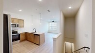 Located at 211 Gilroy Dr in Cordova, TN, this two-story residence offers a clean, modern aesthetic throughout. The main living level is the heart of the home, where an open-concept kitchen and living room flow seamlessly together. The kitchen is well-appointed with warm-toned wood cabinetry, a white countertop island with an undermount sink and matte black faucet, stainless steel appliances including a French door refrigerator, electric range, and microwave, plus a classic white subway tile backsplash. Pendant lighting above the island adds a contemporary touch. Light-toned hardwood-style flooring runs throughout the upper level, lending a bright, cohesive feel. The living area benefits from natural light through a large window and is equipped with a ceiling fan. The generously sized primary bedroom features its own ceiling fan, a large window with blinds, and direct access to a private en-suite bathroom with rich wood vanity cabinetry and a backlit mirror. An additional bedroom on the same floor mirrors the bright, airy style with its own window and ceiling fan. The ground floor houses an attached garage with an automatic opener, polished concrete flooring, and interior access, providing secure and convenient parking or additional storage.