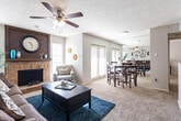 Located at 4415 Northcrest Dr in Midland, Texas, this single-story home offers a well-organized layout with inviting living spaces throughout. The living room serves as the heart of the home, centered around a classic brick fireplace with a striking wood-panel surround that extends to the ceiling. Ceiling fans in each room provide comfort, while natural light streams through multiple windows fitted with blinds. Soft carpeting runs throughout the main living areas, adding warmth underfoot.

The living and dining areas flow seamlessly together, with the dining space accommodating a full dining set and benefiting from a set of glass doors that invite natural light. A mirrored wall in the dining area enhances the sense of openness. The kitchen features warm wood cabinetry, stone-toned countertops, hardwood-style flooring, and full appliances including a range, microwave, and ample storage behind louvered pantry doors.

The bedroom is a calm retreat, finished with plush carpeting, a ceiling fan, and generous wall space. The bathroom is well-appointed with a wood-trimmed vanity, stone-look countertop, wood-framed medicine cabinet mirrors, and a full tub-shower combination with tiled surround. Throughout the home, a textured ceiling treatment adds a consistent architectural detail, tying the spaces together cohesively.