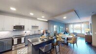 This thoughtfully designed single-floor residence offers a seamless blend of modern style and functional living. The open-concept kitchen is a standout feature, equipped with stainless steel appliances, dual-tone cabinetry pairing white upper cabinets with slate-blue lower cabinets, a marble-style tile backsplash, dark granite countertops, and a central island with bar seating — ideal for both casual dining and entertaining. The kitchen flows naturally into a dedicated dining area and a spacious living room anchored by a bold teal accent wall and floor-to-ceiling windows that frame captivating waterfront views. Hardwood-style flooring runs throughout, lending warmth and continuity to the open layout. The primary bedroom is a serene retreat, featuring a ceiling fan, teal accent wall, large windows with waterfront vistas, and ample storage. Its en-suite bathroom offers dual undermount sinks set in dark granite countertops atop blue cabinetry, with a large framed mirror and a separate shower. The second bedroom is equally well-appointed, with waterfront views, a ceiling fan, and its own bathroom featuring matching dark granite finishes and blue cabinetry. A cohesive palette of blues, grays, and warm wood tones creates a calm, sophisticated ambiance throughout.