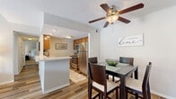 This two-story, 2-bedroom, 2-bathroom home offers a thoughtfully arranged layout across two floors. The main level is the larger of the two and features an open-concept dining room and kitchen combination, along with a separate living room. The kitchen is equipped with stainless steel appliances, warm wood cabinetry, a double basin sink, and durable wood-look flooring. Adjacent to the kitchen, the dining area is accented by a ceiling fan and flows naturally into the living space. A second, cozy living room on the main floor provides an additional area for relaxation. The upper level is highlighted by a dramatic vaulted ceiling in the living area, adding a striking sense of height and openness. Both bedrooms are carpeted and well-lit with natural light from large windows. The primary bedroom is generously sized and includes a walk-in closet with built-in wire shelving. Each bathroom features a wood-toned vanity, bright lighting, and wood-look flooring. A hallway and dedicated closet round out the functional layout. The two-level design, combined with distinct living zones and quality finishes throughout, makes this home both practical and comfortable.