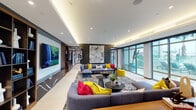 Located on Montrose Boulevard in one of Houston's most dynamic neighborhoods, this single-floor amenity space delivers a sophisticated, gallery-like atmosphere defined by bold contemporary design and curated artwork throughout. The entry area greets visitors with striking geometric tile flooring in gray tones and a sleek marble-accented reception desk, setting an immediate tone of modern elegance.

The expansive main lounge is anchored by a large-scale abstract artwork on a dark charcoal accent wall, flanked by built-in wood bookshelves displaying curated décor and books. Plush gray sectional sofas are accented with vibrant yellow and red throw pillows, while bold patterned area rugs ground the seating areas. A large wall-mounted display screen and cove lighting add warmth and functionality. Floor-to-ceiling glass windows flood the space with natural light and provide views of the outdoor surroundings.

The bar and kitchen area features an expansive white waterfall island with leather barstools, warm wood cabinetry, dark stone countertops, and elegant gold pendant lighting. A vivid pop-art mural lounge offers an energetic contrast, with oversized comic-style wall art and comfortable, compact seating — an ideal creative nook. Throughout, the interplay of marble, warm wood, and curated contemporary art creates a cohesive, vibrant, and inviting communal environment.