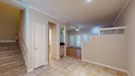 This two-story home is thoughtfully designed with distinct flooring and finishes across each level. The main floor greets visitors with light-toned tile flooring that flows through the entry and kitchen areas, transitioning to warm hardwood in the living spaces. Crown molding runs throughout the main level, adding a refined touch to the neutral-toned walls. A fireplace anchors the living area, while a ceiling fan and large windows with blinds allow natural light to filter in. French doors open to the exterior, enhancing connectivity to the outdoors. The kitchen is equipped with stainless steel appliances, dark granite countertops, light wood cabinetry, and a louvered pantry door for added storage.

A staircase with a glass block accent detail connects the two floors. Upstairs, the bedrooms feature plush carpeting and vaulted ceilings with ceiling fans. The primary bedroom includes mirrored sliding closet doors and a skylight that bathes the room in natural light. An additional carpeted bedroom offers a window with ample natural light. The bathroom includes tile flooring, a glass-enclosed shower and tub combination, dark granite vanity, and light wood cabinetry.