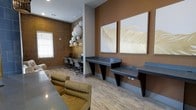 This single-floor space is thoughtfully designed to blend functionality with contemporary aesthetics. The interior showcases a warm, earthy color palette, with a rich terracotta-toned accent wall adorned with two striking large-scale gold and white feather art pieces, lending a sophisticated focal point to the room. Light wood-look flooring runs throughout, complementing the neutral tones and contributing to a bright, open atmosphere.

A dedicated workstation area features sleek, dark floating desks supported by angular geometric bases, providing ample workspace. Adjacent to this, a computer workstation nook is set against a textured, grass cloth-style wall, equipped with multiple monitors and ergonomic mesh office chairs. A cluster of oversized white globe pendant lights overhead adds a sculptural, artistic element to this area.

A plush, mustard-toned lounge chair invites relaxation, offering a comfortable seating option within the space. Natural light filters in through a window fitted with horizontal blinds. Recessed ceiling lighting and carefully curated décor throughout ensure the space remains both practical and visually refined.