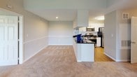 This single-floor residence offers a thoughtfully designed layout that balances comfort and functionality. The living room serves as the central gathering space, highlighted by a tile-surround fireplace and a ceiling fan overhead. A large sliding glass door floods the room with natural light and provides views of the surrounding greenery, creating an inviting ambiance. Soft, neutral-toned carpet flows throughout the living areas and bedrooms.

The kitchen is connected to the dining area via a pass-through counter with dark granite countertops, offering both a visual connection between spaces and practical serving convenience. White cabinetry, a subway tile backsplash, and stainless steel appliances — including a gas range, microwave, and refrigerator — complete the kitchen's clean, modern aesthetic.

The bedrooms are well-proportioned, each featuring plush carpeting, large windows that invite natural light, and ceiling fans for added comfort. One bedroom includes a walk-in closet with built-in shelving, providing generous storage.

Both bathrooms are finished with warm wood-style flooring and white vanities. Each features a tub-shower combination with tiled surrounds, a single-sink vanity, and ample cabinetry for storage, maintaining a clean, practical design throughout.