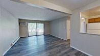 Located at 2201 Woodhollow Ln, Apt 2B, Hammond, IN, this 790 square foot apartment offers a practical and comfortable single-floor layout with 2 bedrooms and 2 bathrooms. The open living room features gray luxury vinyl plank flooring, a wall-mounted air conditioning unit, baseboard heating, and a sliding glass door that opens to a private balcony with outdoor views of surrounding greenery. The adjacent kitchen is equipped with warm oak cabinetry, dark countertops, a white refrigerator, and a white electric range, with matching LVP flooring that flows seamlessly from the living area. Both bedrooms are carpeted in gray tones and include sliding closet doors and windows that bring in natural light — the primary bedroom measures 170 square feet. The two bathrooms each feature oak vanities with white countertops, mirrors with lighted fixtures, and gray LVP flooring. One bathroom includes a tub-shower combination with decorative tile surround, while the second offers a standalone glass-enclosed shower stall. Baseboard heaters are present throughout the unit, providing consistent climate control. The neutral color palette and clean finishes give the apartment a move-in ready appeal.