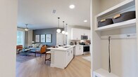 This thoughtfully designed single-floor residence offers 2 bedrooms and 2 bathrooms within a comfortable and efficiently laid-out floor plan. The open-concept kitchen and living area serves as the heart of the home, featuring white shaker cabinetry, a subway tile backsplash, stainless steel appliances including a range, microwave, and dishwasher, and a central island with a built-in sink and pendant lighting overhead. Light wood-style flooring flows throughout the main living area, which is bathed in natural light from large windows and a glass door leading to an outdoor balcony. The primary bedroom is a generously sized retreat with a ceiling fan, large windows, soft carpet, and a walk-in closet outfitted with dual hanging rods and built-in shelving. The en-suite bathroom includes a tiled tub-shower combination. The second bedroom mirrors the same clean design and comfortable scale. A dedicated laundry room houses a full-size side-by-side washer and dryer with open shelving above. Two closets provide ample storage throughout, and a hallway connects the living spaces with ease. The overall aesthetic is modern and cohesive, with neutral tones, recessed lighting, and ceiling fans throughout.