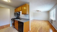 Located at 53 Salmon Brook Dr in Glastonbury, CT, this single-floor residence offers a well-organized layout with consistent design details throughout. The galley-style kitchen is a functional highlight, featuring warm honey-toned wood cabinetry, granite countertops, a subway tile backsplash, and a full suite of appliances including a gas range, stainless steel microwave, dishwasher, and refrigerator. The kitchen opens toward the living area, which is finished with gleaming hardwood floors and a ceiling fan overhead. The open-concept flow between the kitchen and living space creates an airy, connected feel ideal for everyday living and entertaining. The bedrooms continue the hardwood flooring theme and are bright and generously sized. One bedroom benefits from natural light through a window with outdoor views, while the primary bedroom offers the added convenience of dual closets. The bathroom is clean and well-appointed, featuring a granite-topped vanity with an undermount sink, white cabinetry, full tub and shower combination, and tile surround with a privacy window. Textured ceilings and baseboard heating are consistent throughout, and the overall palette of neutral tones and warm wood finishes gives the space a welcoming, cohesive ambiance.