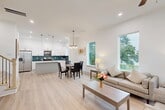 Located at 5302 Kindred Garden Ln in Houston, TX, this modern three-story home offers a well-organized layout across its three levels. The ground floor houses an attached garage with clean white walls and a dedicated entrance. The main living level features an open-concept design combining the living room, dining area, and kitchen into one cohesive space. The kitchen is a standout, boasting white shaker cabinetry, dark countertops, a center island, stainless steel appliances, and a striking teal herringbone tile backsplash, all brightened by natural light from a large window. The dining area is accented by a stylish pendant chandelier and generous windows with outdoor views. The living room features light hardwood-style flooring, recessed lighting, and a ceiling fan. The upper floor hosts all three bedrooms, including a well-proportioned primary suite with dual windows framing lush tree views and a walk-in closet with built-in shelving. Secondary bedrooms are bright with ceiling fans and natural light. Five thoughtfully designed bathrooms with light flooring and clean white finishes serve the home. Throughout, the interiors reflect a crisp, contemporary aesthetic with neutral tones, recessed lighting, and an airy ambiance.
