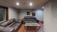 Located at 2835 Rice St in Roseville, Minnesota, this single-floor recreational space is thoughtfully designed for leisure and entertainment. The layout flows seamlessly across distinct functional zones, all unified by warm hardwood flooring and neutral gray walls that lend the space a clean, modern character.

The billiards area serves as a central focal point, anchored by a full-size pool table with a green felt surface and a rich wood frame. Overhead, pendant lighting mounted on a track system illuminates the table with precision, while a wall-mounted cue rack keeps equipment neatly organized nearby. Framed billiards-themed artwork adds personality to the walls throughout this zone.

Adjacent to the billiards area is a comfortable lounge space furnished with deep brown leather sofas and a leather armchair, arranged around a slate-top coffee table with a metal frame. Recessed ceiling lighting provides a relaxed ambiance, complemented by decorative wall art and a tall decorative plant that adds a natural element to the interior.

Further into the space, a dining area with a table and chairs offers a practical gathering spot, visible through an open-concept transition that keeps the entire layout feeling connected and spacious. A wall-mounted air conditioning unit ensures year-round comfort. The overall design balances functionality with a welcoming, casual atmosphere well-suited for social gatherings and recreation.