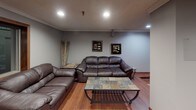 Located at 2835 Rice St in Roseville, Minnesota, this single-floor recreational space is thoughtfully designed for leisure and entertainment. The layout flows seamlessly across distinct functional zones, all unified by warm hardwood flooring and neutral gray walls that lend the space a clean, modern character.

The billiards area serves as a central focal point, anchored by a full-size pool table with a green felt surface and a rich wood frame. Overhead, pendant lighting mounted on a track system illuminates the table with precision, while a wall-mounted cue rack keeps equipment neatly organized nearby. Framed billiards-themed artwork adds personality to the walls throughout this zone.

Adjacent to the billiards area is a comfortable lounge space furnished with deep brown leather sofas and a leather armchair, arranged around a slate-top coffee table with a metal frame. Recessed ceiling lighting provides a relaxed ambiance, complemented by decorative wall art and a tall decorative plant that adds a natural element to the interior.

Further into the space, a dining area with a table and chairs offers a practical gathering spot, visible through an open-concept transition that keeps the entire layout feeling connected and spacious. A wall-mounted air conditioning unit ensures year-round comfort. The overall design balances functionality with a welcoming, casual atmosphere well-suited for social gatherings and recreation.