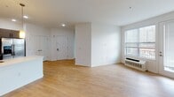 Located at 56 Broad Street in Bloomfield, NJ, this well-appointed two-bedroom, two-bathroom residence offers a thoughtfully designed single-level layout. The open-concept living and dining area is highlighted by light hardwood flooring, recessed lighting, and a large window with blinds that invites natural light throughout the space. The kitchen is outfitted with stainless steel appliances — including a gas range, over-the-range microwave, and side-by-side refrigerator — complemented by textured dark wood cabinetry, a neutral tile backsplash, quartz countertops, and pendant lighting over a kitchen island with a built-in sink. Both bedrooms feature plush carpeting, ample natural light from large windows with blinds, and individual climate control units. The primary bedroom includes a walk-in closet. The two bathrooms are finished with large-format tile flooring, dark wood vanity cabinetry, white quartz countertops, and wall-mounted medicine cabinets. One bathroom features a soaking tub, while the other includes a glass-enclosed walk-in shower. Clean white walls and consistent modern finishes throughout the residence contribute to a bright, contemporary ambiance.