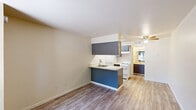Located at 824 Gurley Pl in Prescott, Arizona, this efficiently designed single-floor studio makes smart use of its intimate footprint. The open layout is anchored by warm hardwood-style flooring that runs continuously throughout the space, lending a cohesive and clean aesthetic.

The kitchen is a functional highlight, featuring a peninsula with a light-toned countertop, an undermount stainless steel sink, and slate-blue cabinetry that extends to overhead upper cabinets. A white range, refrigerator, and microwave complete the appliance package, while a ceiling fan overhead adds comfort and air circulation.

The main living area is bright and open, with a large window that frames views of the surrounding natural landscape and a balcony railing, bringing the outdoors in. The entry door features a classic six-panel design, and a wall-mounted HVAC unit provides climate control.

The bathroom is well-appointed with matching slate-blue vanity cabinetry and a light marble-style countertop, complemented by a large mirror with vanity lighting. Adjacent to the bathroom is a walk-in closet fitted with built-in shelving, offering practical storage solutions.

The space is finished with neutral warm-beige walls and white trim throughout, creating a clean, inviting atmosphere well-suited for comfortable single-occupancy living in the heart of Prescott.