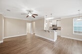 This 1,090-square-foot, single-story residence at 4000 Penuche Way in Holly Springs, NC offers a well-designed 2-bedroom, 2-bathroom layout ideal for comfortable everyday living. The open-concept kitchen and living room serves as the heart of the home, featuring warm hardwood-style flooring, crown molding, and a ceiling fan. The kitchen is equipped with white cabinetry, granite countertops, stainless steel appliances including a range and microwave, and a peninsula island with a built-in sink and pendant lighting — flowing seamlessly into the living area, which is bathed in natural light from multiple windows with white plantation shutters. The primary bedroom spans 180 square feet with plush carpeting, a ceiling fan, and direct access to an en-suite bathroom and a walk-in closet fitted with wire shelving. The second bedroom also features carpet flooring, a ceiling fan, and ample natural light. Both bathrooms include hardwood-style flooring and vanities with white cabinetry. A dedicated laundry room houses a full-size washer and dryer with overhead storage cabinets. Two closets with wire rack shelving provide additional storage. Three hallways connect the spaces efficiently, completing this thoughtfully arranged home.
