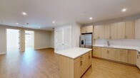 Located at 684 Main Ave in Passaic, NJ, this well-appointed 2-bedroom, 1-bathroom unit offers a thoughtfully designed layout with modern finishes throughout. Light wood flooring flows seamlessly across the entire space, creating a warm and cohesive aesthetic in every room. The open-concept kitchen and living area serves as the heart of the unit, anchored by a sleek kitchen featuring light wood cabinetry, white subway tile backsplash, stainless steel appliances, and a central island with a crisp white countertop — ideal for both cooking and casual dining. Recessed lighting illuminates the space effectively. The primary bedroom is generously sized, bathed in natural light from a large window framed by navy roller shades, and topped with a striking sputnik chandelier that adds a modern touch. The second bedroom also features louvered closet doors and recessed lighting, offering functional storage and a clean design. The full bathroom is finished with large-format marble-style floor and wall tiles, a floating wood vanity with an integrated white basin, an illuminated LED mirror, and a tub-shower combination with a sleek black-framed glass door. The unit's neutral palette and modern fixtures create a bright, move-in-ready living environment.
