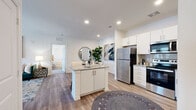 This thoughtfully designed 2-bedroom, 2-bathroom single-floor residence offers a comfortable and cohesive living experience across a well-utilized floor plan. The open-concept living, dining, and kitchen area forms the heart of the home, anchored by warm wood-look flooring and recessed lighting throughout. The kitchen is outfitted with stainless steel appliances, including a full-size refrigerator, range, microwave, and dishwasher, complemented by crisp white cabinetry, granite countertops, a subway tile backsplash, and a central island that doubles as additional prep and storage space. The dining area flows naturally from the kitchen, providing an inviting setting for everyday meals. The living room features a ceiling fan, large windows that bring in natural light, and direct access to an exterior door. The spacious primary bedroom includes plush carpeting, a ceiling fan, and access to a dedicated closet. Both bathrooms are finished with granite-topped vanities, white cabinetry, and wood-look tile flooring, with one featuring a tiled shower-tub combination. A dedicated in-unit laundry room with full-size washer and dryer adds everyday convenience. The overall aesthetic is clean, modern, and move-in ready.