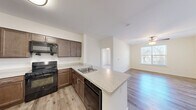 This 1-bedroom, 1-bathroom unit offers a thoughtfully designed single-floor layout that maximizes functionality and comfort. The open-concept living and kitchen area serves as the heart of the space, where light-toned walls and wood-style flooring create a clean, welcoming atmosphere. A ceiling fan overhead provides both comfort and a subtle design accent, while a window allows natural light to brighten the living area.

The kitchen is well-equipped with rich dark-brown cabinetry extending to the upper walls, light-colored countertops, and a full suite of black appliances including a refrigerator, range, and over-the-range microwave. A peninsula with a built-in sink and additional cabinet storage doubles as a breakfast bar, seamlessly connecting the kitchen to the living space.

The bedroom is a comfortable retreat featuring plush carpeting, a ceiling fan with light fixture, and a window that invites natural light. A dedicated closet offers convenient storage, keeping the room organized and functional.

The bathroom is finished with tile flooring, a dark-wood vanity with ample cabinet space, and a full tub-and-shower combination with white tile surround and grab bars. Clean white walls and bright fixtures complete the space with a crisp, practical finish throughout.