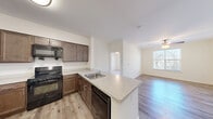This 1-bedroom, 1-bathroom unit offers a thoughtfully designed single-floor layout that maximizes functionality and comfort. The open-concept living and kitchen area serves as the heart of the space, where light-toned walls and wood-style flooring create a clean, welcoming atmosphere. A ceiling fan overhead provides both comfort and a subtle design accent, while a window allows natural light to brighten the living area.

The kitchen is well-equipped with rich dark-brown cabinetry extending to the upper walls, light-colored countertops, and a full suite of black appliances including a refrigerator, range, and over-the-range microwave. A peninsula with a built-in sink and additional cabinet storage doubles as a breakfast bar, seamlessly connecting the kitchen to the living space.

The bedroom is a comfortable retreat featuring plush carpeting, a ceiling fan with light fixture, and a window that invites natural light. A dedicated closet offers convenient storage, keeping the room organized and functional.

The bathroom is finished with tile flooring, a dark-wood vanity with ample cabinet space, and a full tub-and-shower combination with white tile surround and grab bars. Clean white walls and bright fixtures complete the space with a crisp, practical finish throughout.