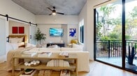 Located at 2281 N Lois Ave in Tampa, FL, this thoughtfully designed one-bedroom, one-bathroom residence offers a compelling blend of industrial and contemporary aesthetics across a single level. The living room is an immediate standout, boasting soaring exposed concrete ceilings, warm wood-look flooring, and large windows that flood the space with natural light. A sliding barn door adds a stylish architectural touch, while direct access to a private balcony with lush greenery views extends the living area outdoors. The open layout connects seamlessly to the kitchen, which features marble-look countertops and a sleek range hood. The bedroom continues the concrete ceiling motif, offering a serene retreat with a dedicated workspace and direct sightlines to a cozy sitting nook. A spacious walk-in closet with custom wood shelving and ample hanging storage serves the bedroom. The bathroom is finished with a backlit vanity mirror, dark hardware, a glass-enclosed walk-in shower, and wood-look flooring for a clean, modern look. A dedicated laundry room with a stacked washer and dryer and built-in shelving completes this well-appointed residence.