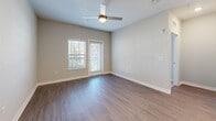 This single-floor unit is thoughtfully designed with a clean, contemporary aesthetic throughout. The open-concept kitchen serves as a central highlight, featuring granite countertops, a large island with pendant lighting, white cabinetry paired with gray lower cabinets, a tile backsplash, and a full suite of stainless steel appliances including a French door refrigerator, electric range, microwave, and dishwasher. Wood-look plank flooring extends through the kitchen and living areas, contributing to a cohesive, modern feel.

The living area is bright and open, benefiting from natural light through multiple windows and a glass exterior door that provides direct outdoor access. A ceiling fan adds both function and style to the space.

Bedrooms are carpeted for comfort and include generous windows with blinds. At least one bedroom connects to a walk-in closet equipped with multi-tiered wire shelving systems.

The primary bathroom offers dual granite-topped vanities, wood-look flooring, a large mirror, and a glass-enclosed walk-in shower. A secondary bathroom includes a tiled soaking tub and shower combination with grab bars, along with wood-look flooring. Neutral tones throughout create a calm, welcoming ambiance.