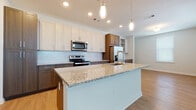 Located at 5380 Desoto Rd in Sarasota, Florida, this thoughtfully designed single-floor residence offers a seamless blend of modern finishes and functional living spaces. The open-concept kitchen serves as the heart of the home, showcasing a large granite-topped island with an integrated sink, pendant lighting, and a clean subway tile backsplash. Two-tone cabinetry—combining crisp white upper cabinets with warm wood-toned lower cabinets—pairs beautifully with stainless steel appliances, including a French door refrigerator, range, and built-in microwave. Light wood-look flooring flows throughout the main living areas, enhancing the bright and airy ambiance. The bedrooms feature plush neutral carpeting and tray ceilings, with generous windows allowing ample natural light. The primary bathroom is appointed with granite countertops, a wood-toned vanity, a glass-enclosed shower with tile surround, and convenient access to a walk-in closet. A secondary bathroom includes a full soaking tub with tiled surround. A dedicated laundry area with a full-size washer and dryer adds everyday convenience. The overall design is clean, contemporary, and well-appointed, making this Sarasota residence a comfortable and stylish place to call home.