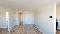 Located at 1240 Sherman St in Denver's Capitol Hill neighborhood, this single-floor unit offers a clean, modern aesthetic throughout. Wood-look luxury vinyl flooring runs consistently across the living areas and bedrooms, providing a cohesive and low-maintenance foundation. Neutral gray wall tones complement the bright white trim and panel-style doors, creating a light and airy atmosphere.

The galley-style kitchen is well-appointed with gray upper cabinetry, dark lower open shelving, light stone-pattern countertops, a mosaic tile backsplash, and black stainless appliances including a range and refrigerator. A flush-mount ceiling light and under-cabinet range hood add functional detail.

The bedrooms are generously proportioned, each featuring wood-look flooring and closet storage — including a spacious double-door closet in the primary bedroom and a sliding-door closet in the secondary bedroom. One bedroom benefits from a large window with horizontal blinds that frames views of the Denver urban skyline, allowing ample natural light to fill the room.

The bathroom features a full tub-shower combination with white subway tile surround and brushed nickel fixtures, set against warm beige walls. The overall layout, as shown in the 3D model, offers an efficient and functional flow between the living, kitchen, and sleeping areas.