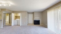 This single-floor residence offers a practical and comfortable layout across several well-defined living spaces. The spacious living room serves as the heart of the home, featuring plush carpeting, a classic fireplace with a white mantel shelf, and a sliding glass door that fills the room with natural light and provides direct access to an outdoor patio. Track lighting overhead adds a functional and modern touch to the open living area.

The galley-style kitchen is efficiently designed with white cabinetry, light quartz-style countertops, and wood-look vinyl flooring. It comes equipped with black appliances, including a refrigerator, electric range, microwave, and dishwasher, along with a stainless steel sink. A pass-through counter connects the kitchen to the living area, enhancing the open feel.

Two well-sized bedrooms are finished with soft carpeting and neutral-toned walls. One bedroom features a ceiling fan with a light fixture and a window for natural light, while the other includes a walk-in closet with built-in shelving. Each bathroom is clean and functional, offering a tiled tub/shower combination.

A dedicated laundry closet with a full-size washer and dryer adds everyday convenience. Textured ceilings and consistent warm-toned walls unify the space throughout.