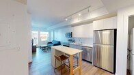 This 1-bedroom, 1-bathroom unit in Calgary, AB offers a thoughtfully designed open-concept layout that maximizes every square foot. Light hardwood-style flooring flows throughout, complementing the clean, contemporary aesthetic found in each room.

The kitchen is a standout feature, equipped with stainless steel appliances including a refrigerator, electric range, microwave, and dishwasher. Crisp white cabinetry extends to the ceiling for ample storage, while a subway tile backsplash adds a modern touch. A central island with seating provides a casual dining area, seamlessly connecting the kitchen to the living space. Track lighting overhead ensures the area is well-lit and functional.

The living room is bright and airy, with large windows inviting natural light and direct access to a private balcony. A wall-mounted mini-split unit provides climate control for year-round comfort.

The bedroom is a calm retreat, featuring a large window with outdoor views and warm hardwood-style flooring, providing a quiet and restful environment.

The bathroom is finished in a clean, all-white palette with a combined tub and shower, a single vanity with an integrated sink, and a large mirror.

Additional highlights include in-suite laundry and a dedicated entrance, rounding out this practical and modern urban residence.