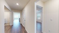 This single-story home presents a clean, modern aesthetic with a neutral color palette and consistent dark hardwood-style flooring running throughout the main living and bedroom areas. The open-concept layout connects the living room to the kitchen, with natural light streaming in through multiple windows fitted with horizontal blinds and a glass door that opens to the outdoors.

The kitchen is a functional centerpiece, equipped with granite countertops featuring subtle veining, gray-toned shaker-style cabinetry, and a full suite of stainless steel appliances including a refrigerator with ice dispenser, electric range, and over-the-range microwave. A central island with an integrated sink adds additional prep and storage space.

The bedrooms are generously sized, each featuring hardwood-style flooring, neutral walls, and windows that bring in natural light. The primary bathroom includes a dual-sink vanity with gray cabinetry, a large mirror, a walk-in glass-enclosed shower, and tile flooring. A secondary full bathroom offers a tub-shower combination and matching tile floors.

A dedicated laundry room with a full-size washer and dryer, wire shelving, and tile flooring rounds out this well-organized, move-in-ready home.