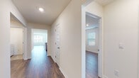 This single-story home presents a clean, modern aesthetic with a neutral color palette and consistent dark hardwood-style flooring running throughout the main living and bedroom areas. The open-concept layout connects the living room to the kitchen, with natural light streaming in through multiple windows fitted with horizontal blinds and a glass door that opens to the outdoors.

The kitchen is a functional centerpiece, equipped with granite countertops featuring subtle veining, gray-toned shaker-style cabinetry, and a full suite of stainless steel appliances including a refrigerator with ice dispenser, electric range, and over-the-range microwave. A central island with an integrated sink adds additional prep and storage space.

The bedrooms are generously sized, each featuring hardwood-style flooring, neutral walls, and windows that bring in natural light. The primary bathroom includes a dual-sink vanity with gray cabinetry, a large mirror, a walk-in glass-enclosed shower, and tile flooring. A secondary full bathroom offers a tub-shower combination and matching tile floors.

A dedicated laundry room with a full-size washer and dryer, wire shelving, and tile flooring rounds out this well-organized, move-in-ready home.