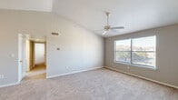 This single-floor residence offers a practical and comfortable layout across two bedrooms, two bathrooms, a combined kitchen and living area, a hallway, and two closets. The living room immediately impresses with its vaulted ceiling and ceiling fan, soft neutral-toned carpet, and a large window that draws in natural light and offers outdoor views of surrounding greenery. The kitchen is efficiently designed with a galley-style layout, featuring taupe cabinetry, white countertops, light tile flooring, and black appliances including a refrigerator, electric range, and dishwasher. The spacious primary bedroom continues the vaulted ceiling detail, is fitted with plush carpet, a ceiling fan, and a generous window with outdoor views. It is complemented by a walk-in closet with wire shelving for ample storage. The second bedroom is well-sized with carpet flooring, neutral walls, and a bright window overlooking the exterior. Both bathrooms are cleanly finished; one features wood-look flooring, a single-sink vanity with wood cabinetry, a large mirror with overhead lighting, and a shower-tub combination. Throughout, the space maintains a cohesive, neutral color palette that creates a calm and inviting atmosphere.