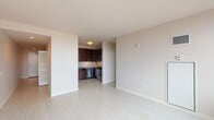 This single-floor unit at 150 Forest Ave in Oak Park, IL offers a clean, modern design throughout. The open living area features light wood-style flooring and neutral walls, flowing into a well-appointed kitchen with dark espresso cabinetry, granite countertops, a tile backsplash, and stainless steel appliances including a gas range, dishwasher, and microwave. The bedroom is carpeted and features a large window with panoramic elevated views. The living area also benefits from floor-to-ceiling windows showcasing treetop cityscape views. The bathroom includes a granite-topped vanity with dark cabinetry and tile flooring. A hallway entry provides closet storage and recessed lighting.