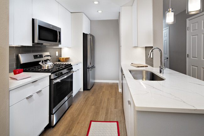 Premier Scheme kitchen with flat white cabinetry, white marbled quartz countertops, grey subway tile backsplash, stainless steel appliances, and hard surface flooring - Avalon Melville