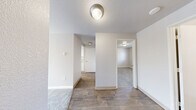 Located at 3701 S Orchard St in Tacoma, Washington, this one-bedroom, one-bathroom unit offers a well-organized, single-floor layout with a clean, neutral aesthetic throughout. The living room serves as the heart of the space, featuring soft gray carpeting, a classic wood-burning fireplace with a tile hearth, and a baseboard heating system. Natural light filters through the windows, lending a bright, airy feel to the room.

The kitchen is efficiently designed with white shaker-style cabinetry, gray countertops, warm wood-look vinyl flooring, and a full suite of white appliances including a refrigerator, range, and dishwasher. An overhead light fixture provides ample illumination, and a hallway connects the kitchen to the rest of the unit.

The bedroom is a quiet, comfortable retreat with plush gray carpeting, a window overlooking the outdoors, and a baseboard heater. A closet is accessible via the connecting hallway, which links the main living areas to the private quarters of the unit.

The bathroom is clean and functional, featuring wood-look vinyl flooring that complements the kitchen, a combined tub and shower with white surrounds, and a vanity with a granite-style countertop. Brushed nickel fixtures add a modern touch throughout. The overall ambiance is calm, bright, and move-in ready.