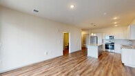 Located at 748 Bates St in Indianapolis, Indiana, this well-appointed one-bedroom, one-bathroom unit offers a thoughtfully designed layout across a single floor. The open-concept kitchen and living area serves as the heart of the home, featuring light wood-toned cabinetry, a subway tile backsplash, granite countertops, and a full suite of stainless steel appliances including a refrigerator, range, microwave, and dishwasher. A central island with pendant lighting above provides additional prep space and casual seating. Warm hardwood-style flooring flows throughout the main living areas, complementing the bright, neutral color palette. The living area receives natural light through large windows and a sliding glass door that opens to a private balcony with outdoor views. The bedroom is carpeted for comfort and includes a window with neighborhood views, offering a quiet retreat. Three closets provide ample storage throughout the unit. The bathroom is finished with large-format tile surrounding a soaking tub and shower combination, granite vanity, and wood-style flooring. A dedicated laundry area with a stacked washer and dryer adds everyday convenience. The overall design is clean, contemporary, and functional.